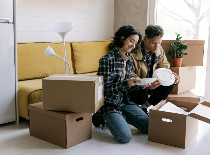 A woman and man examine plates that they have pulled out of moving boxes.