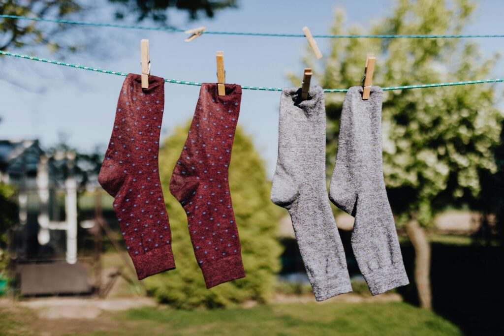 Two pairs of socks hang on a clothesline on a sunny day.