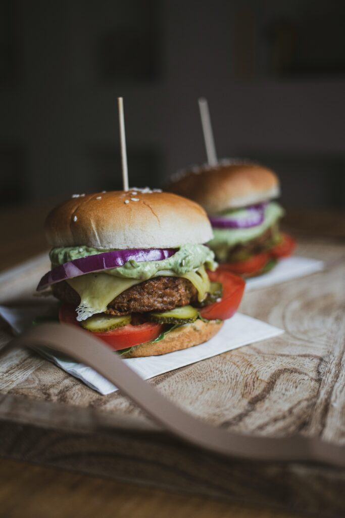 Two Beyond Burgers topped with tomatoes, pickles, red onions and other vegetables.