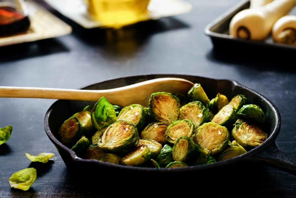 A cast iron frying pan containing sautéed Brussels sprouts halves.