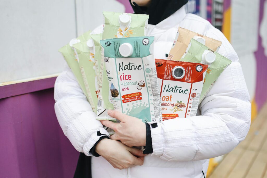 A woman holds Tetra Paks of plant-based milk.