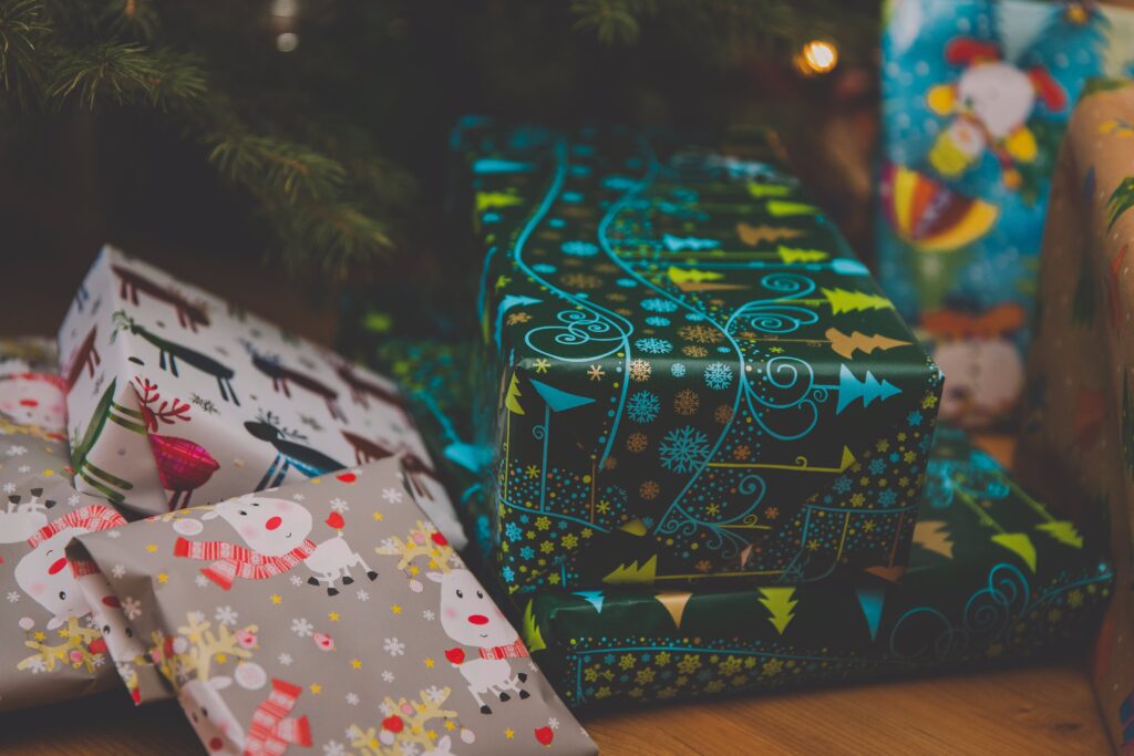 A pile of presents wrapped in grey and dark green wrapping paper with Christmassy patterns.